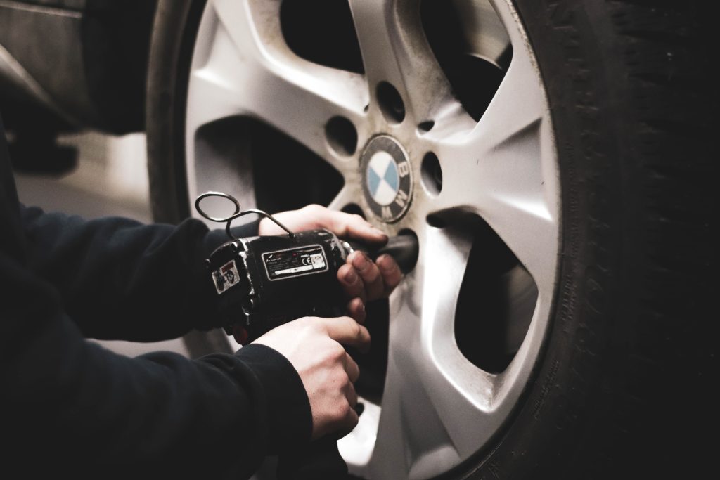 mechanic unscrewing bolts off a bmw car wheel